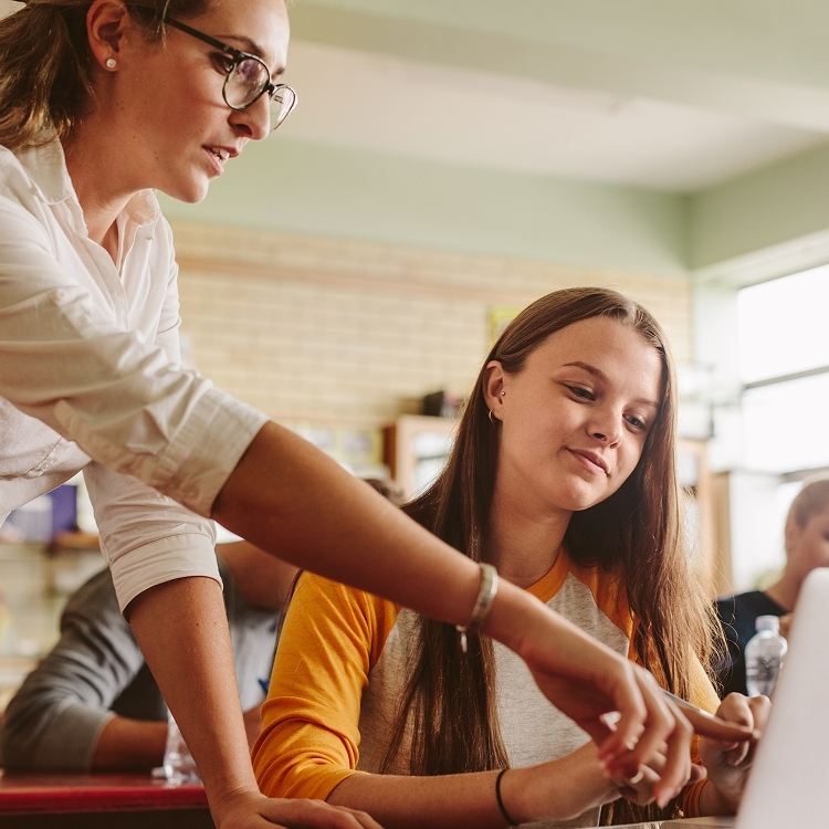 Teacher with student looking at a laptop