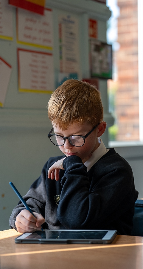 Young student using iPad in classroom