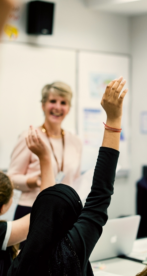 Teacher in classroom with students hands raised